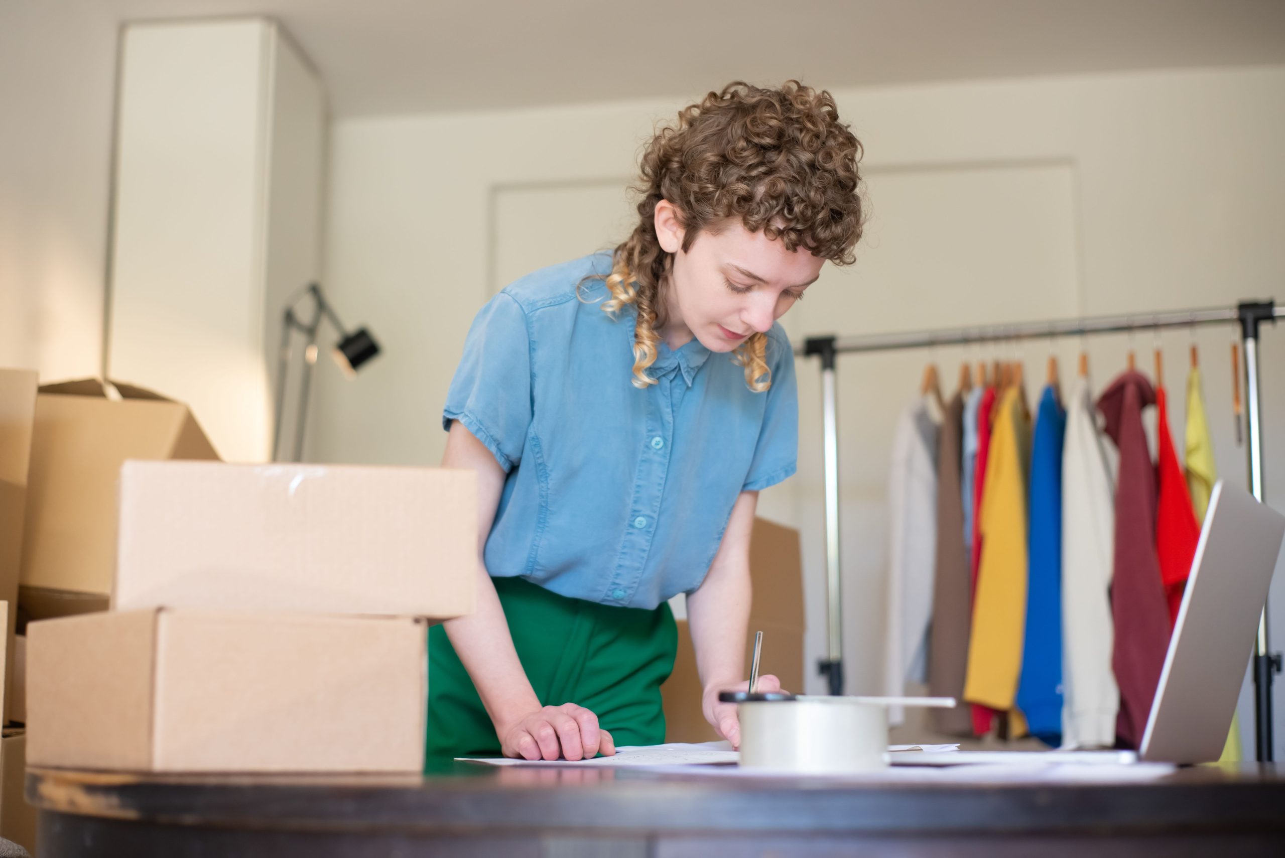 Mujer emprendedora organizando pedidos y cajas en su tienda de ropa